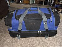 Front and top view of large blue and black duffel bag with dual handles and buckle closures.