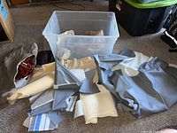 Wide view of the storage bin and numerous pieces of fabric, leather, and vinyl in various colors and textures spread on carpet.