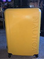 Yellow Nautica suitcase with embossed logo on front, showing the smooth hard shell exterior, black wheels, and handles.