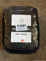Heated vest apparel packaging including user guide and power bank label visible through plastic pouch on front.