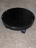 Top view of black circular spinning roller with small holes on surface