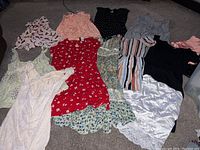 Overview of all dresses laid out on the floor showing variety in style, color and fabrics