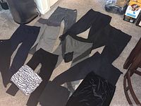 All 11 pairs of women's stretch pants laid out on the floor showing various colors and styles including mesh panels and zebra print