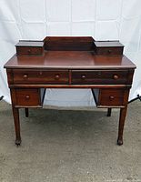 Front view of antique wooden desk showing drawers and legs