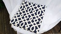 Folded curtain panel showing navy blue fabric with cream geometric pattern.