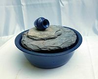 Wide shot of decorative indoor water feature with basin, slate platform, and electric pump on top