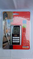 Front view of Maverick ET-8 Roast Alert thermometer in original packaging showing probe, LCD screen, and buttons.