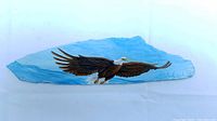 View of hand-painted flying bald eagle on blue shale rock on white background