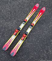 Pair of K2 Escape junior downhill skis with Tyrolia bindings mounted, shown from above laying parallel on asphalt.
