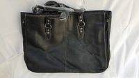 Front view of large black leather purse showing buckle strap details and overall shape.