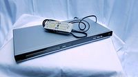 Philips DVD player with remote control placed on a white fabric background showing front and top of device