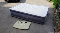 Air mattress fully inflated on ground with carrying bag placed beside it showing the Intex brand logo.