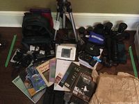 Overview of lot showing tripod, camera bags, assorted lenses, camera body, printer, books, chargers, batteries, and accessories