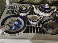 Photo showing the teapot, creamer, sugar bowl, and six side plates with blue and white pattern and gold trim.