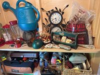 Overview of shelf holding blue watering can, bird feeders, bird seed bags, clocks, and miscellaneous smaller items.