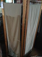 Photo showing two panels from front and side, highlighting beige fabric and wood frame