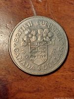 Obverse side of the 1871-1971 British Columbia centennial commemorative coin showing coat of arms and dogwood blossoms.
