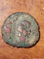 Photo of ancient bronze coin obverse side with profile of Emperor Constantine I visible, showing corrosion and wear.