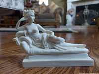 Side-angle view of cultured marble semi-nude reclining sculpture of Pauline Bonaparte as Venus Victrix showing figure reclining on a chaise lounge with draped cloth and detailed features.
