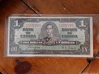 Front of 1937 Canadian One Dollar banknote in protective sleeve showing portrait of King George VI and bilingual text.