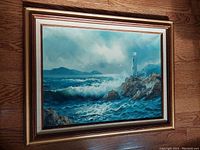 Framed full view of the oil painting depicting the lighthouse on a rocky coast with a turbulent sea and flying birds.