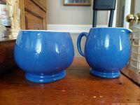 Vintage Moorcroft Liberty Blue sugar bowl and creamer shown from the front, highlighting the smooth speckled blue glaze.
