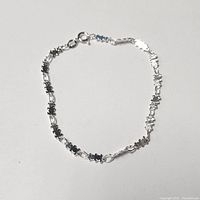 Photo showing the silver bracelet laid flat with the floral patterned chain and spring ring clasp visible
