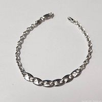 Front view of a sterling silver 7 inch bracelet featuring five larger oval links and smaller interlocking round links with a lobster claw clasp.