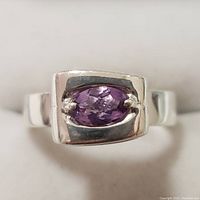 Front view of the silver ring showing the purple oval amethyst gemstone bezel set with prongs in a polished rectangular silver mounting.