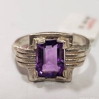 Close-up photo of a sterling silver ring with a rectangular emerald-cut amethyst gemstone in the center and stepped side band design.