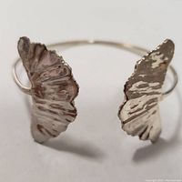 Close-up photo of a silver bracelet with butterfly-shaped ends shown frontally