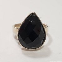 Close-up front view of pear-shaped black onyx set in sterling silver ring.