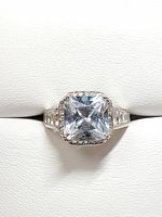 Top view of silver ring with large clear square princess-cut cubic zirconia center stone and baguette side stones.
