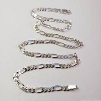 Full view of the silver Figaro link necklace laid out to show length and design.