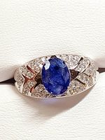 Front view of silver men's ring showing oval sapphire and surrounding cubic zirconia stones.