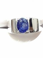 Front view of men's silver ring showing oval blue sapphire and surrounding cubic zirconia accent stones on polished silver band.