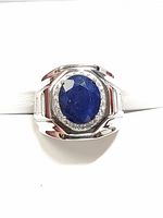 Front view of silver ring showing large oval faceted blue sapphire surrounded by clear cubic zirconia stones in a polished silver setting.