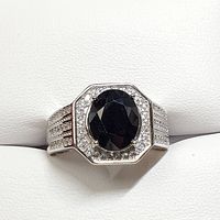 Front view of men's silver ring with large oval black sapphire surrounded by clear cubic zirconia stones, showing detailed faceting and halo design.