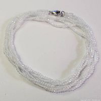 Full view of the necklace coiled to show the white quartz beads and overall design.