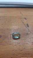 Oval cut sky blue aquamarine gemstone on wooden surface showing size and shape.