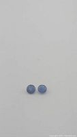 Pair of round cut blue sapphire gemstones approximately 5mm in diameter, side by side on a plain background.
