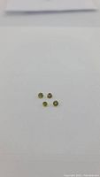 Four small round greenish-yellow sphene gemstones arranged on a white background.