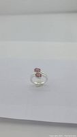 Front angled view of cherry red garnet silver ring showing two oval garnet stones set on split shank band