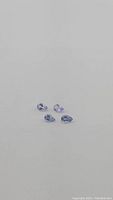 Four pear cut Tanzanite stones laid on white background with some shadowing, showing color and shape