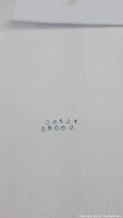 Top view of the 10 round cut aquamarine gemstones arranged in a line on a white background to show uniformity in size and clarity.