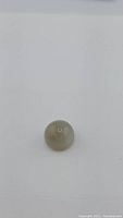 Round smoky grey moonstone cabochon on white background showing top view.