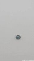 Oval cut natural teal blue sapphire gemstone, approximately 7x5mm showing its color and clarity from top view.