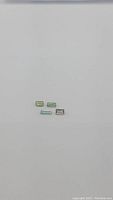 Four natural green tourmaline baguette cut gemstones arranged on a white background.