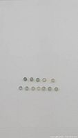 12 untreated fancy sapphires in two rows showing different colors under natural lighting on white background