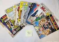 Photo showing a spread of 14 assorted MAD magazines from the 1990s with colorful illustrated covers spread in a fan shape on a white background.